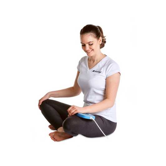 Frau sitzt aufrecht und verwendet den Biomag A6P2 Magnetfeldtherapie Applikator für gezielte lokale Behandlung.