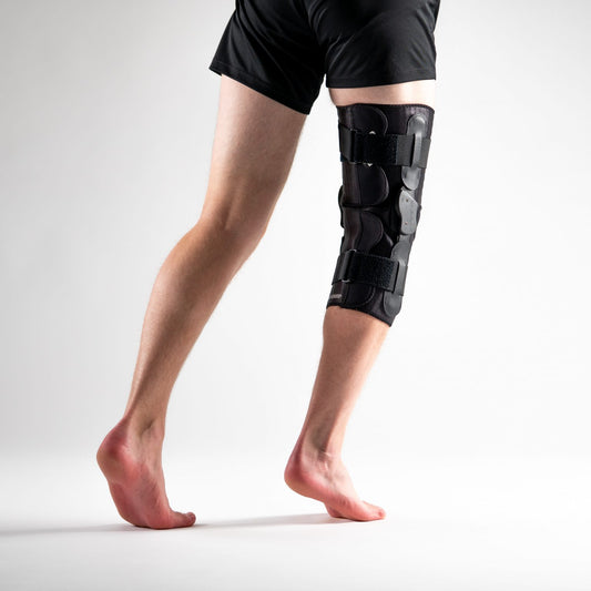 ULTRAWRAP Kniebandage am rechten Bein, Rückansicht, schwarze Softbrace mit seitlichen Scharnieren und verstellbaren Klettverschlüssen.