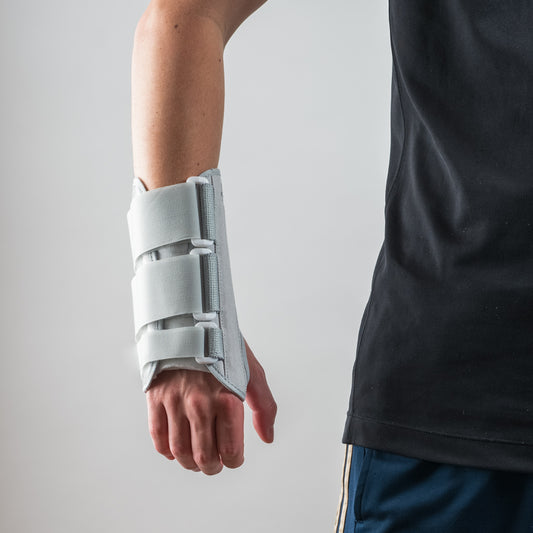 Eclipse Wrist Brace Handschiene in grau, getragen am Handgelenk, Arm gestreckt, Hand locker nach unten zeigend.
