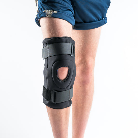 Frontansicht der NEOMAX Kniebandage am rechten Bein, schwarze Bandage mit Alu-Gelenken und offener Patella.