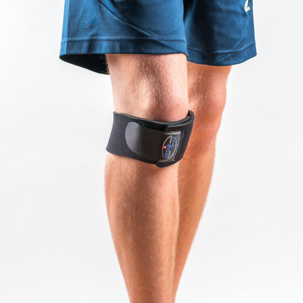 Orthoswiss Mini Kniebandage schwarz, Frontansicht am Bein getragen, unterhalb der Kniescheibe für gezielten Halt fixiert.