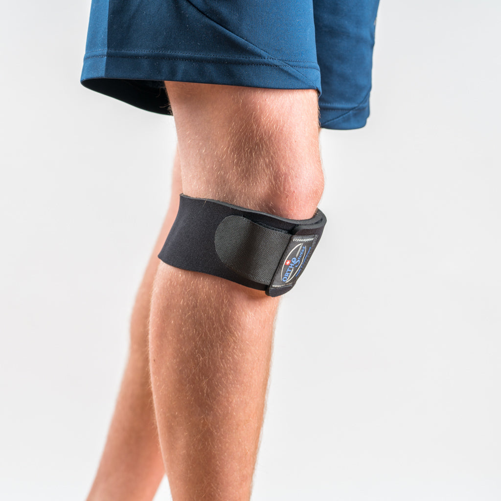 Orthoswiss Mini Kniebandage schwarz, seitliche Ansicht am Bein getragen, unterhalb der Kniescheibe positioniert.