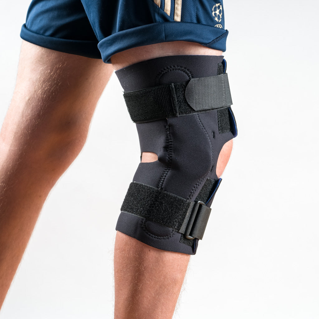 Wrap Around Kniebandage in Schwarz am rechten Bein, Seitenansicht, stehend