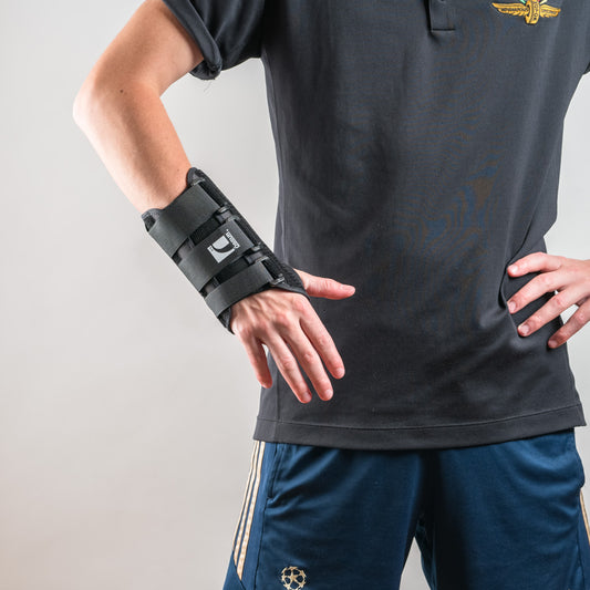 Formfit Handgelenkschiene getragen, Person steht frontal, Hände in die Hüften gestützt, Schiene gut sichtbar.