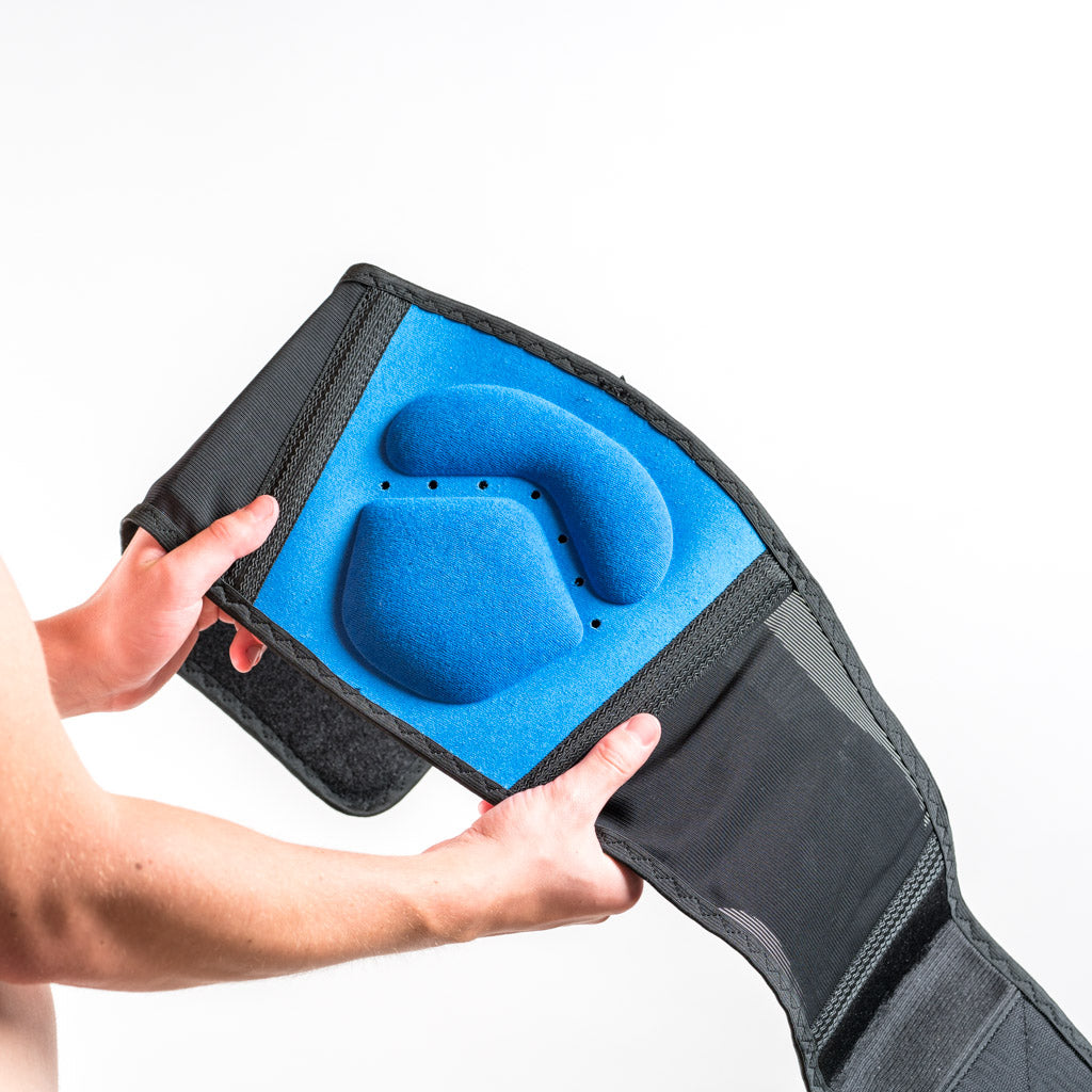 FORMFIT BACK SUPPORT Rückenbandage mit blauer Lumbal-Pelotte, Nahaufnahme beim Einsetzen in das Bandagenfach. 