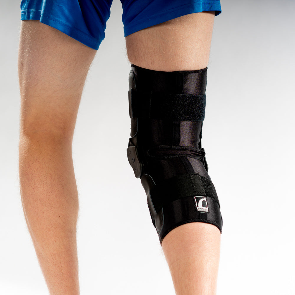 ULTRAWRAP Kniebandage am rechten Bein, Rückansicht, schwarze Bandage mit Scharnieren und Klettverschlüssen.