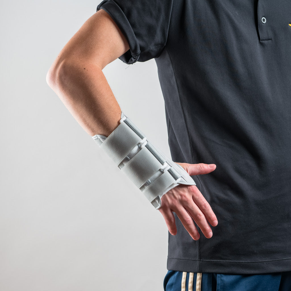 Grey Eclipse wrist brace on the wrist, arm bent at the side, hand turned slightly downward and inward.