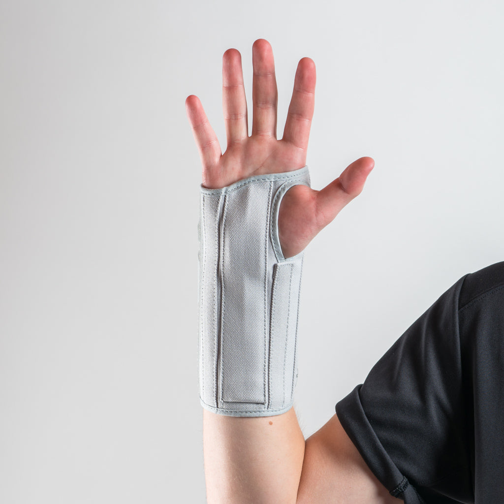 Eclipse Wrist Brace Handschiene in grau, Arm angewinkelt, Hand offen erhoben, Handfläche zeigt nach vorne.