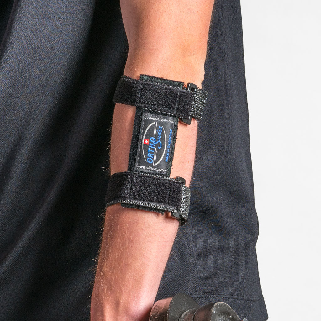 Black OrthoSwiss EPI FIX tennis brace on the forearm, close-up on the side with visible logo, arm hanging loosely.