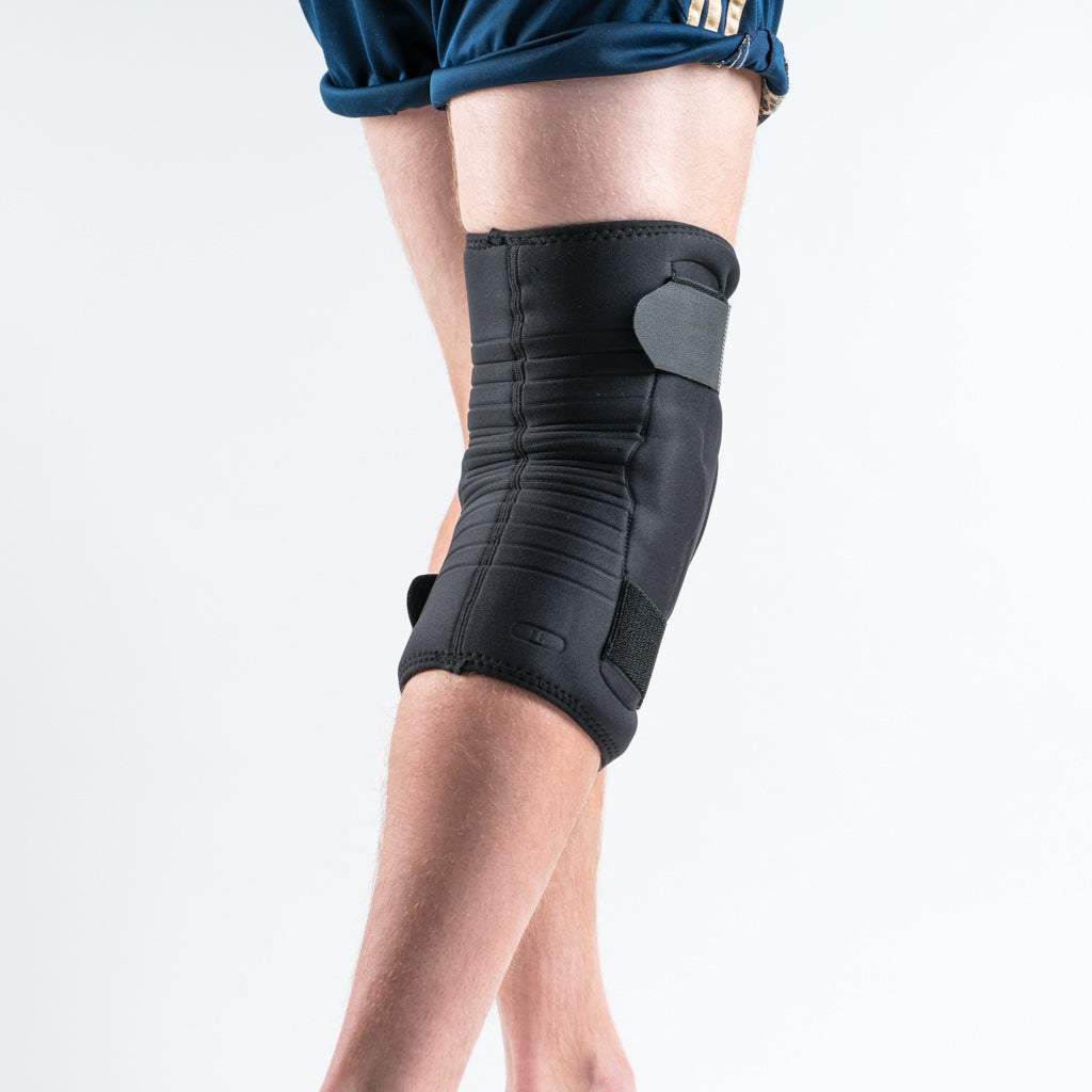 Rückansicht der NEOMAX Kniebandage am rechten Bein, schwarze Bandage mit glatter Rückseite und Klettverschluss. 