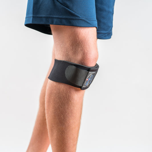 Orthoswiss Mini Kniebandage schwarz, seitliche Ansicht am Bein getragen, unterhalb der Kniescheibe positioniert. 