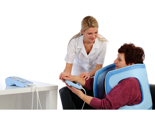 Patient trägt blauen AL115-3D-e COMBI Omega 3D Applikator während einer Magnetfeldtherapie, unterstützt von Therapeutin.